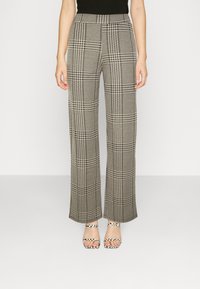 Wide-leg trousers in black and white check pattern, featuring a high waist, smooth fabric texture, and clean lines. Strappy heeled sandals underneath.