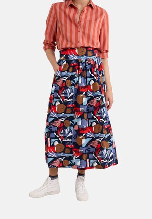 Multicolored skirt with a geometric pattern, featuring red, blue, and brown accents, paired with a striped orange shirt and white sneakers.