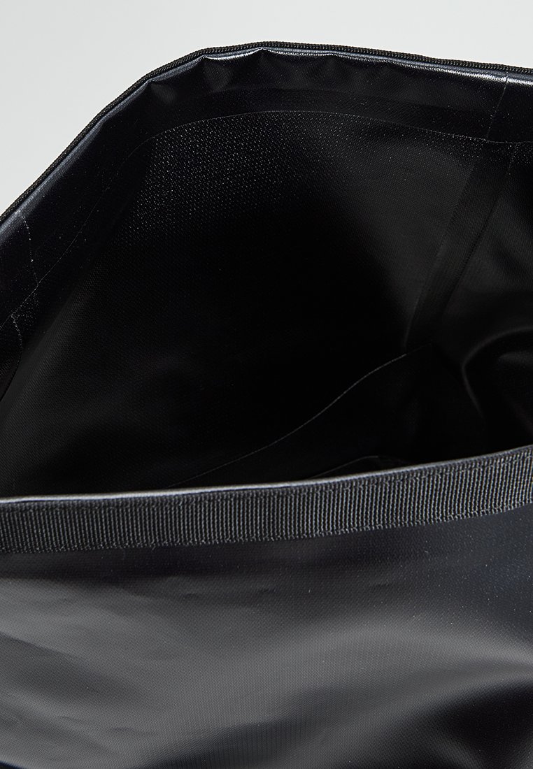 Sac fourre-tout noir avec un intérieur texturé, des poignées robustes et un extérieur lisse. Le design présente une large ouverture pour un accès facile.