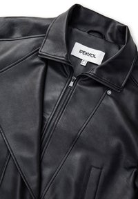 Giubbotto di pelle nera con colletto e chiusura a zip. Presenta cuciture diagonali e tasche frontali. L'etichetta riporta "IPEKYOL." Texture liscia.