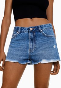 Shorts vaqueros con dobladillo deshilachado, lavado azul claro, diseño de cinco bolsillos y cierre frontal de botones. Presentan un ligero desgaste y detalles desgastados.