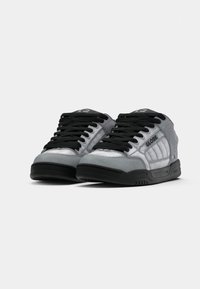 Pair of gray Globe brand sneakers with black laces, black soles, and padded sides, shown from a low front angle.