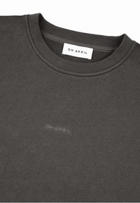 Tmavě šedá mikina s kulatým výstřihem, měkkou texturou a jemně vyraženým logem značky "OH APRIL" na přední straně.