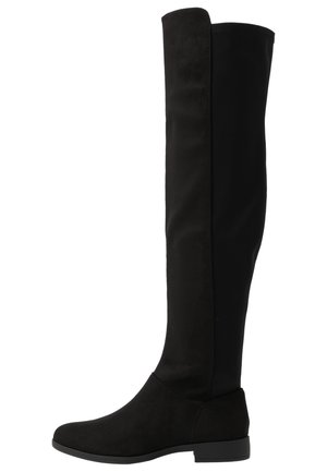 Bottes noires jusqu'aux genoux avec un mélange de matériaux noirs lisses et texturés. Elles présentent une semelle plate et un design simple sans embellissements.