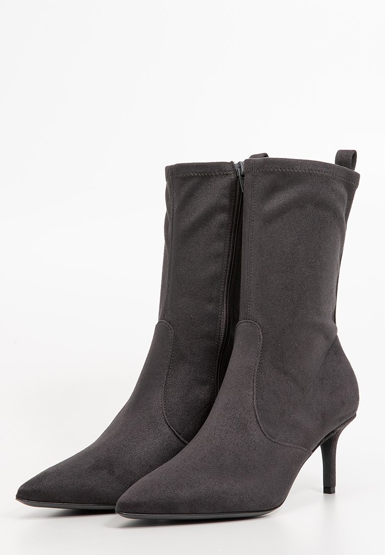 Schwarze faux Wildleder-Ankle-Boots mit spitzem Zehenbereich, seitlichem Reißverschluss und schlankem Heeldesign. Texturierte Oberfläche mit dezenten Nähdetails.
