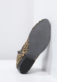 Leopard-print shoe with a textured surface, flat black sole, and a side buckle detail; color palette features shades of brown and black.