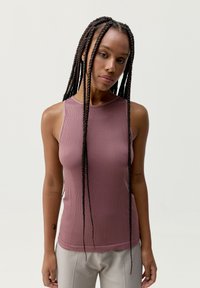 Ribbade, ärmlösa toppar i mjukt mauve-tyg. Har en hög halsringning och en figurnära silhuett som framhäver plaggets eleganta design.