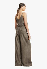 Completo marrone a righe composto da un top con scollo a V e sottili spalline e pantaloni a gamba larga, realizzato in un tessuto texturizzato.