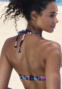 Zwarte en bloemen bikini top met verstelbare strikjes in de nek. Voorzien van een haaksluiting en blauwe, roze en groene bloemenpatronen.