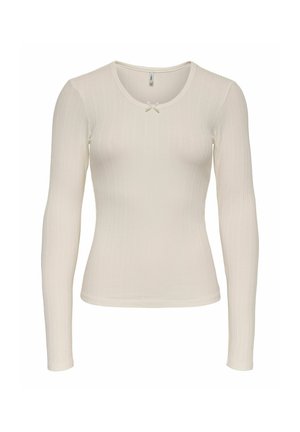 T-shirt à manches longues en tissu côtelé doux couleur crème, avec un col rond et un petit nœud blanc en accent sur la poitrine.
