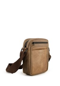Brun læder-crossbody-taske med en frontlomme med lynlås, justerbar brun stofrem og stikninger. Brandlogo er præget på forsiden.