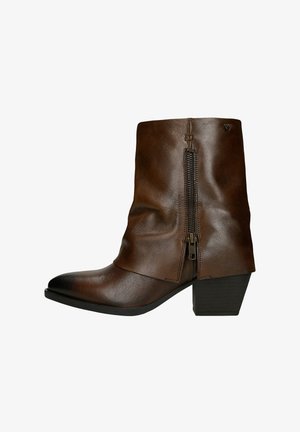 Bottine en cuir marron à design décontracté, avec fermeture éclair latérale, bout carré et talon épais, présentant une texture lisse et des accents minimalistes.