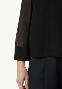 Schwarzer Pullover mit teilweise transparentem Ärmel, strukturiertem Finish, taillierten Bündchen und einem glatten, einfarbigen Körperteil.