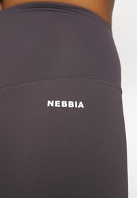 Gray leggings made of stretchy material, featuring a smooth texture and a white "NEBBIA" logo on the side.