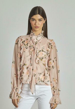 Blumenbluse aus zartem pinkfarbenem Stoff, mit Rüschen entlang der Vorderseite und den Ärmeln, einer Schleife am Halsausschnitt und gerafften Manschetten.