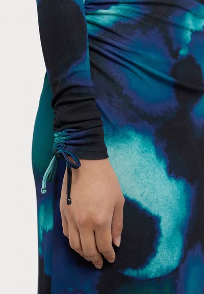 Robe à manches longues présentant un motif tourbillonnant bleu et noir. Le matériau a une texture lisse. Poignet à fronces réglable avec cordons.