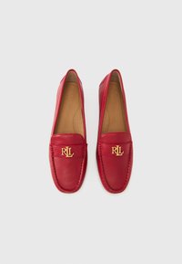 Rdeči usnjeni loaferji z gladko teksturo, z zlatim logotipom "RL" spredaj in šivnimi detajli ob robovih.