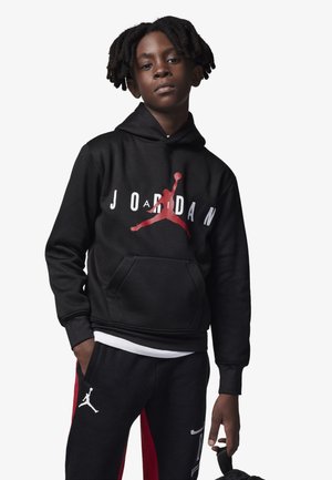 Felpa nera con logo "JORDAN" rosso e silhouette Jumpman. Abbinata a pantaloni tuta neri e rossi con dettagli del logo. Tessuto morbido, vestibilità standard.