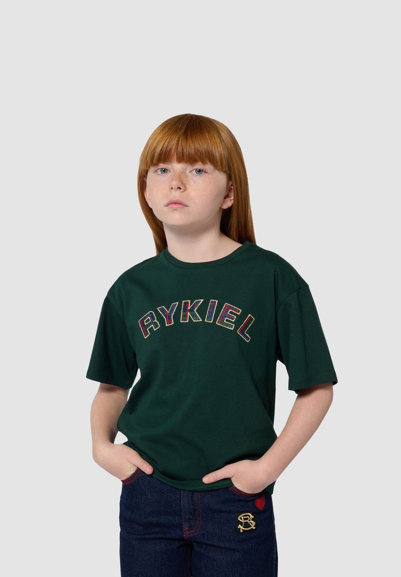 Groen katoenen t-shirt met gedurfde multicolor "RYKIEL" borduursel op de borst. Gepaarde met donkere spijkerbroeken met rode stikselaccenten.