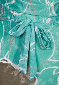 Turkoosikangas, jossa on solmittu nauha vyötäröllä, abstrakteja valkoisia viivoja ja hienovaraisia kultaisia yksityiskohtia kuviollisella taustalla. Raskas pinta.