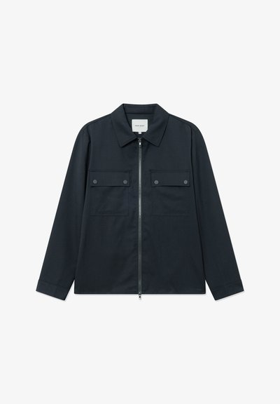 Chaqueta azul marino con cremallera frontal, mangas largas y dos bolsillos en el pecho. Presenta un cuello clásico y un diseño limpio y minimalista.