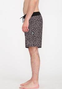 Pantalones de baño negros con patrones abstractos blancos, cinturilla elástica con cordón de ajuste y un pequeño detalle de logo cerca del dobladillo.