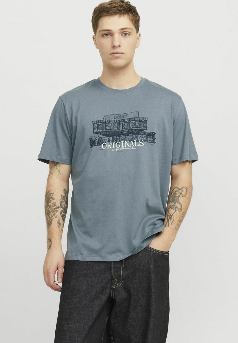 Tricou din bumbac gri cu un design grafic ce include textul "ORIGINALS" în alb, mâneci scurte și o croială lejeră.