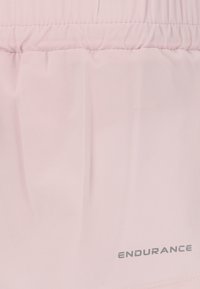 Vaaleanpunaiset kangasshortsit, joissa on kerätty vyötärö ja heijastava "ENDURANCE"-logo helmassa; sileä tekstuuri.