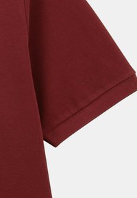 Chemise bourgogne à manches courtes avec une texture douce, présentant un col rond classique et un ourlet fini au niveau des manches.