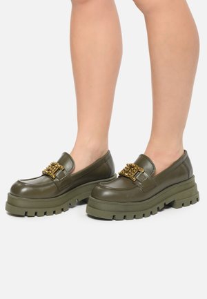 Chaussures à enfiler vert olive en cuir, dotées d'une semelle plateforme épaisse et de détails en chaîne dorée à l'avant.