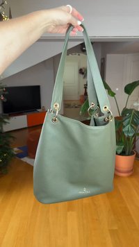 Πράσινη τσάντα κουβάς από δερματίνη με δύο λουριά, μεταλλικά στοιχεία σε χρυσό τόνο και λογότυπο στο κάτω μέρος. Ιδανική για καθημερινή χρήση.