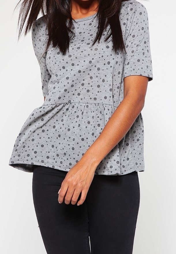 Top corto gris de manga corta con diseño de peplum, que presenta un estampado de lunares en gris más oscuro. Está hecho de una tela suave, ofreciendo un ajuste relajado.