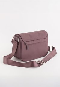 Lilla nylon crossbody taske med klaplukning, justerbar strop og subtile syninger. Har en frontlomme med lynlås.