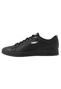 Zapatillas Puma negras con parte superior de cuero suave, puntera redonda, diseño con cordones y suela de goma texturizada con detalles de logo.