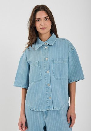 Svetlomodrá denimová košela s krátkymi rukávmi, zapínaním na gombíky, dvoma prednými vreckami a vertikálnymi pruhmi. Mäkka textúra a uvoľnený strih.
