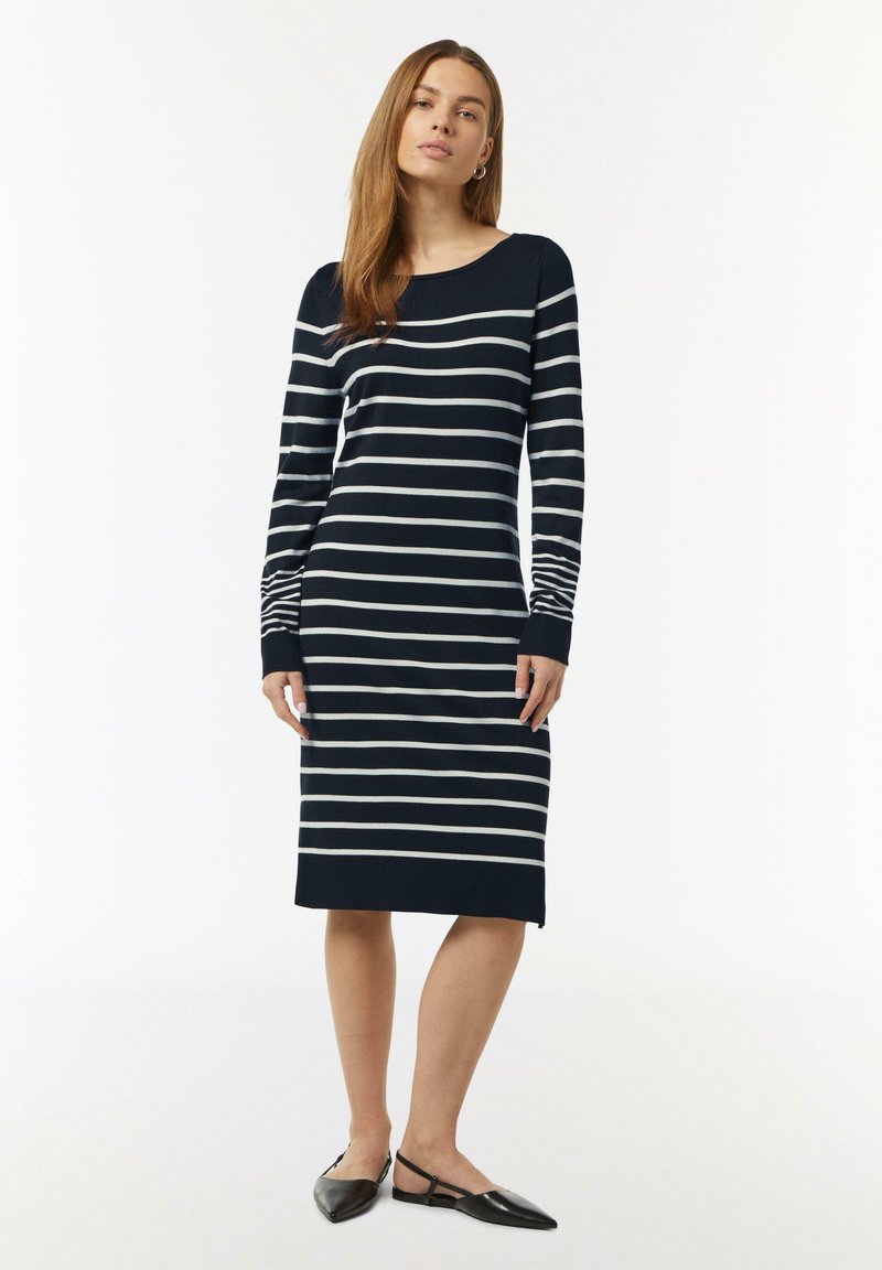 Langärmliges Kleid mit Navy- und weißen Streifen, Rundhalsausschnitt, figurbetonter Passform und Seitenschlitzen am Saum, kombiniert mit schwarzen Ballerinas.