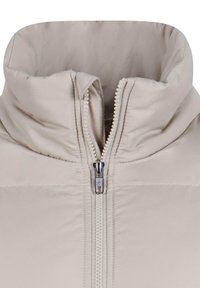 Doudoune beige avec col haut, fermeture éclair centrale et texture matelassée. La fermeture éclair est métallique avec une languette en tissu.