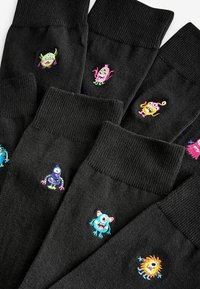 Black socks featuring colorful, whimsical monster designs embroidered on the fabric. Diverse colors and expressions create playful accents.