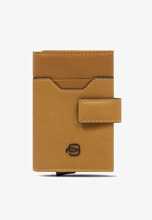 Cartera compacta de cuero marrón claro con cierre de presión, solapa superior texturizada y un pequeño logo negro en el centro inferior frontal.