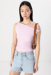 Lys lilla, en-sides topp med rynkedetaljer, parret med lyseblå denim shorts med frayed kanter og et brunt bælte.
