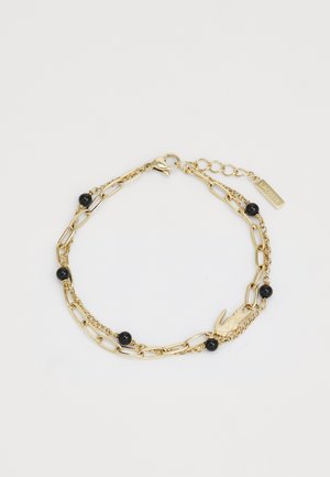 Gold chain bracelet with black beads, featuring a mix of elongated and link chain designs, and a clasp with a lobster-shaped accent.