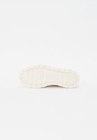 Semelle de basket blanche, en caoutchouc texturé avec motif en losanges, comportant un logo en relief. Construction épaisse et durable conçue pour l'adhérence.