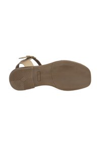 Bruine sandaal met een platte zool, voorzien van een beige enkelband en een decoratieve gesp. De onderkant heeft een gestructureerd grippatroon.