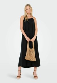 Svart ärmlös maxiklänning med en samlad halsringning, kombinerad med en beige vävd väska och bruna klacksandaler, mot en minimalistisk bakgrund.