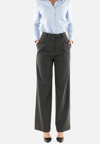 Pantaloni a gamba larga grigi realizzati in tessuto testurizzato con pieghe frontali e tasche laterali, abbinati a una camicia azzurra a maniche lunghe con bottoni.