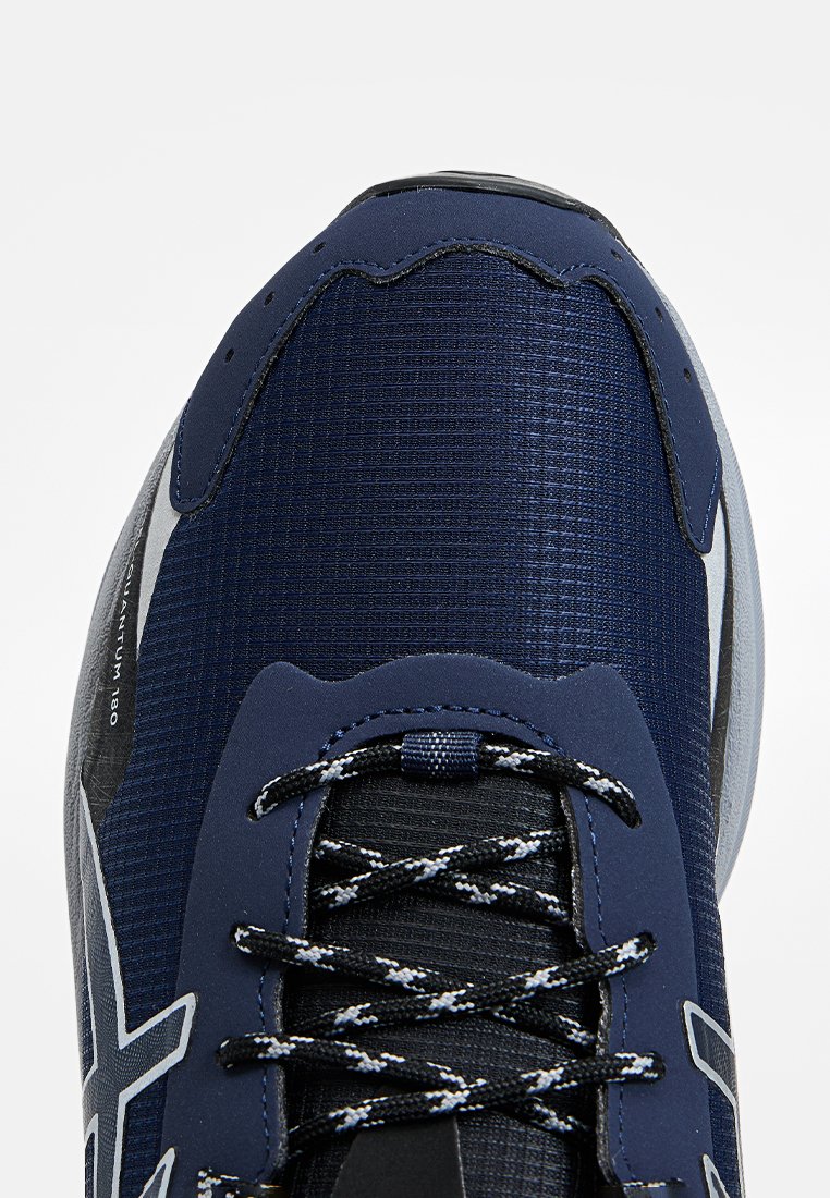 Vista dall'alto di una scarpa sportiva blu navy con lacci neri e bianchi, tessuto texturizzato e bordi della suola grigia.