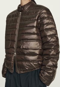 Brown puffer jacket with horizontal quilting, high neckline, and zip closure. Smooth, shiny texture with side pockets and elasticized cuffs.