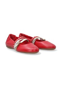 Red leather flat shoes with a pointed toe, featuring a metallic strap with decorative studs and a flexible brown sole.