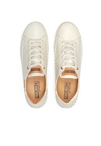 Zapatillas de piel blanca con punta redonda, costura decorativa y cierre de cordones. El interior presenta una plantilla marrón con un detalle de logo.