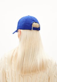 Blauwe honkbalpet met een gebogen klep en verstelbare band, gezien van achteren. Heeft een gestructureerde stof en een klein labeldetail.